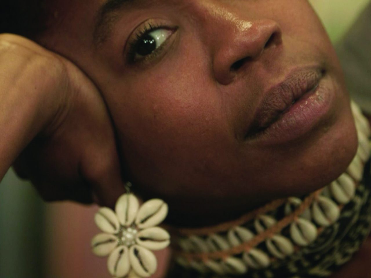 A close up of someones face looking at the camera, they are leaning to the side on their hand.