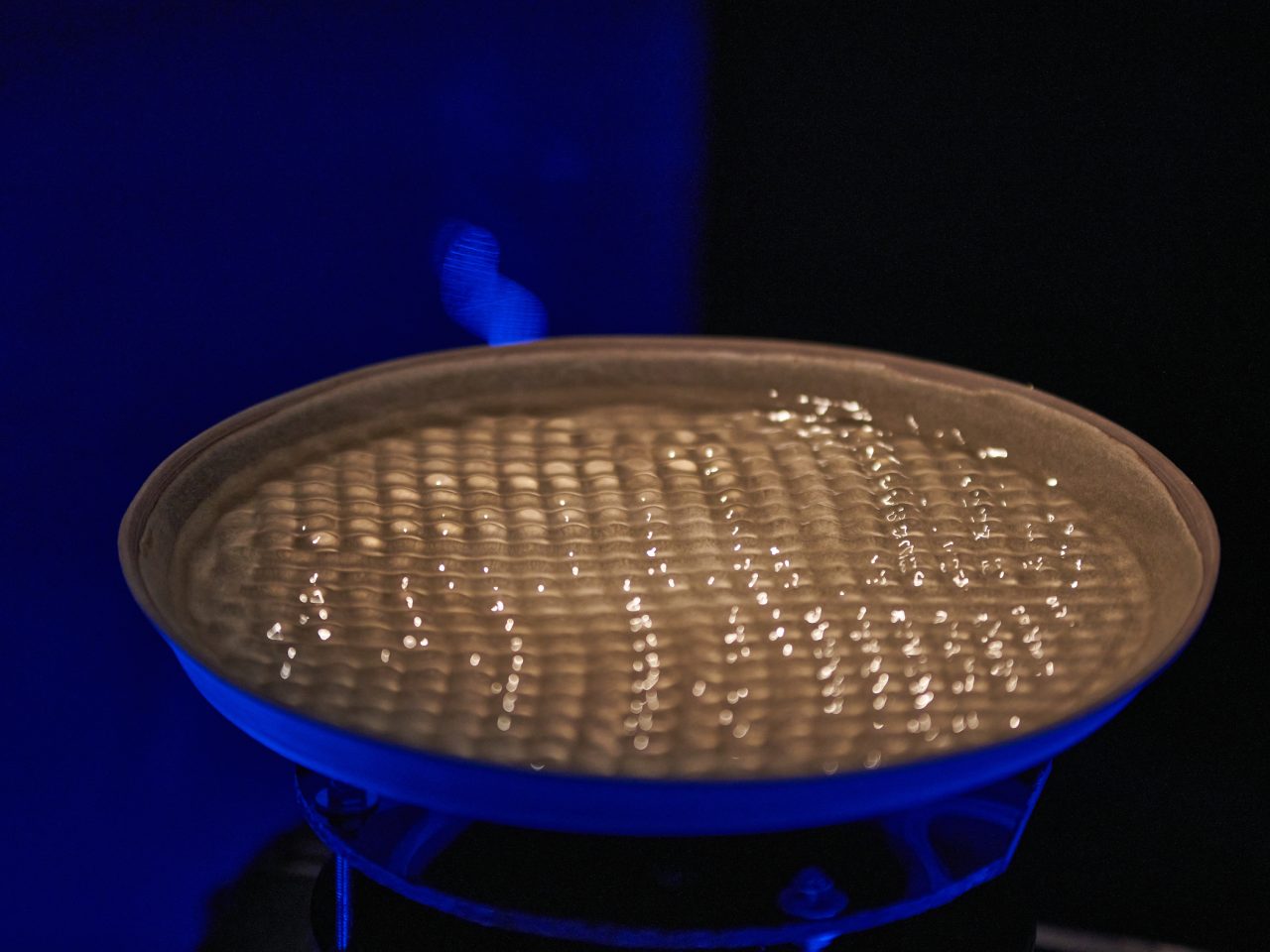 a bowl of vibrating water, the space is lit up with blue lighting