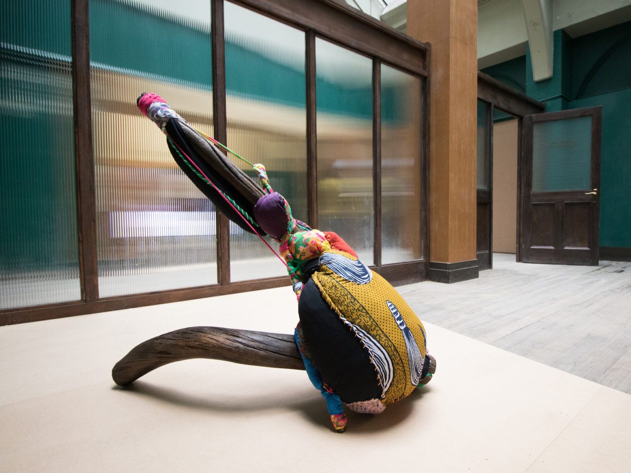 A sculpture made up with colourful and patterned fabrics and stitching, creating an abstract figure