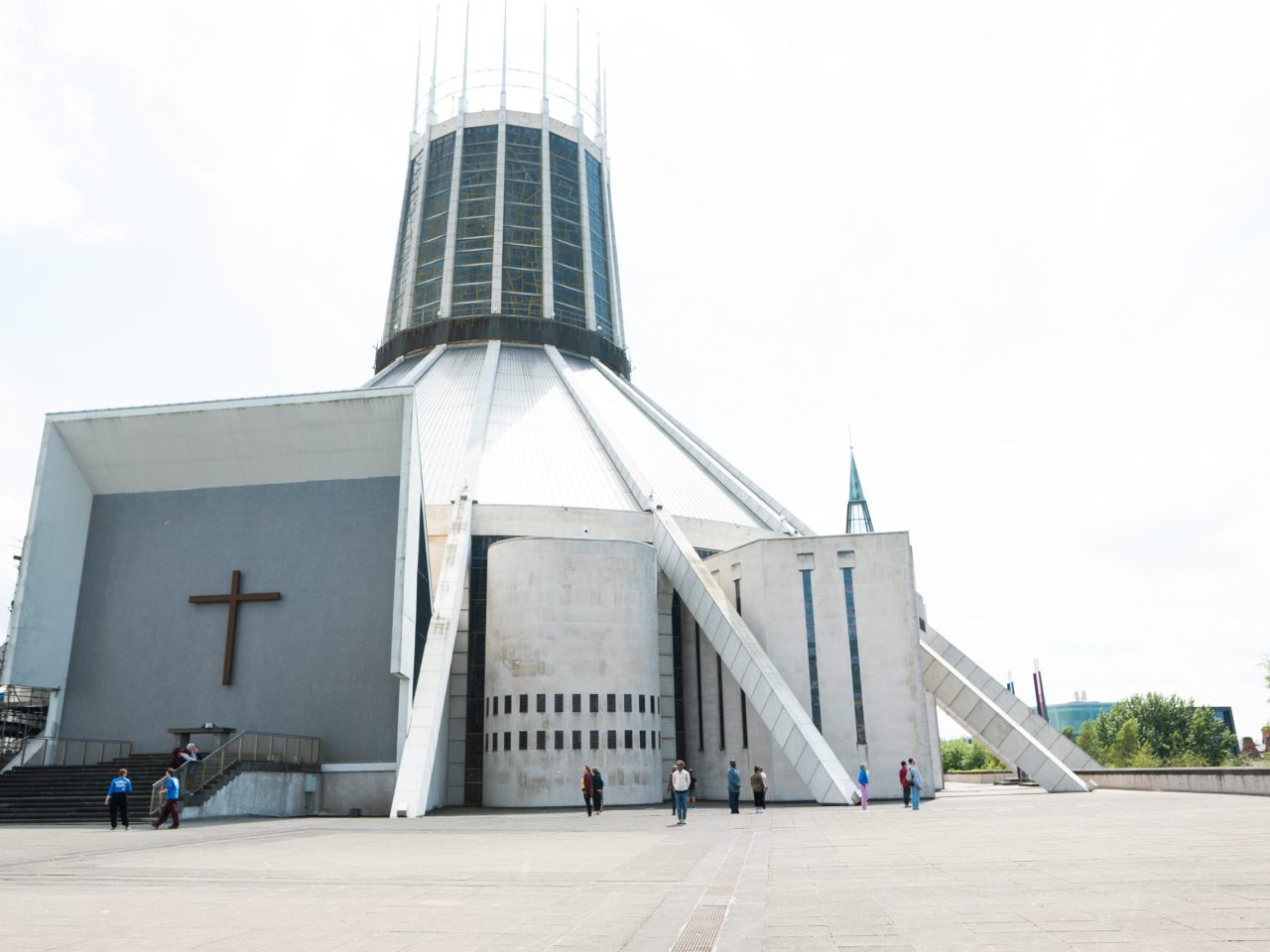 People standing equal distance apart, all turning away from each other. They are standing outside Liverpool Metropolitan Cathedral.