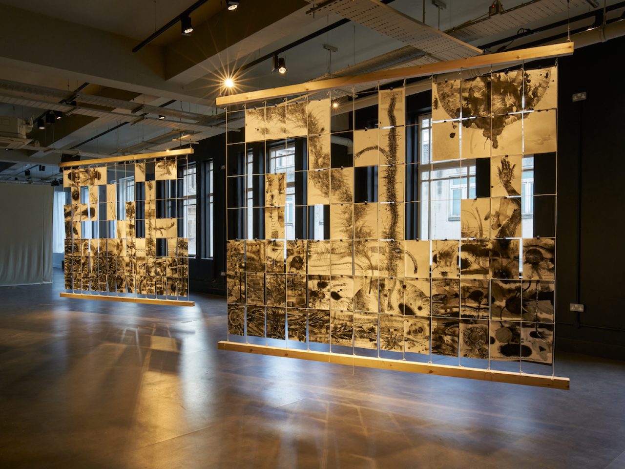 Black ink drawings on pieces of white paper stacked vertically, forming 2 hanging artworks