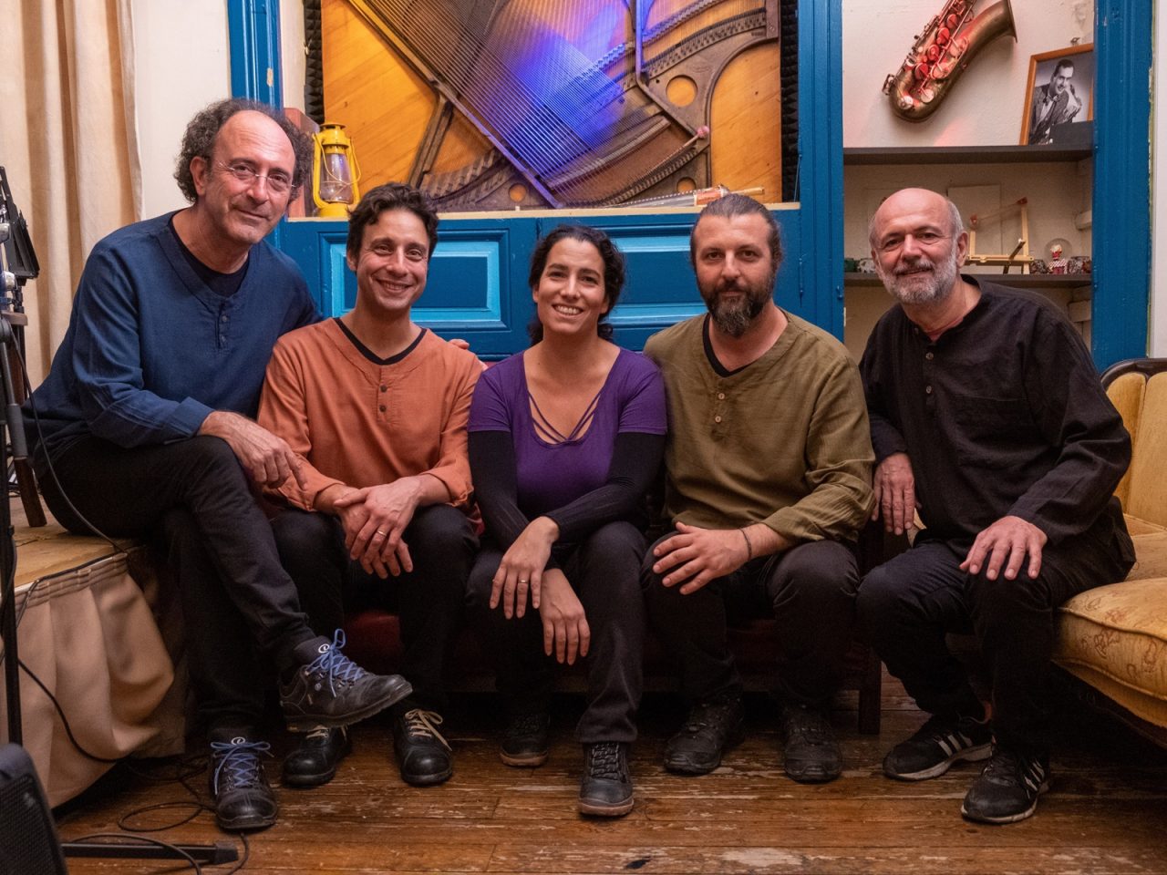 A group portrait of five people facing the camera smiling