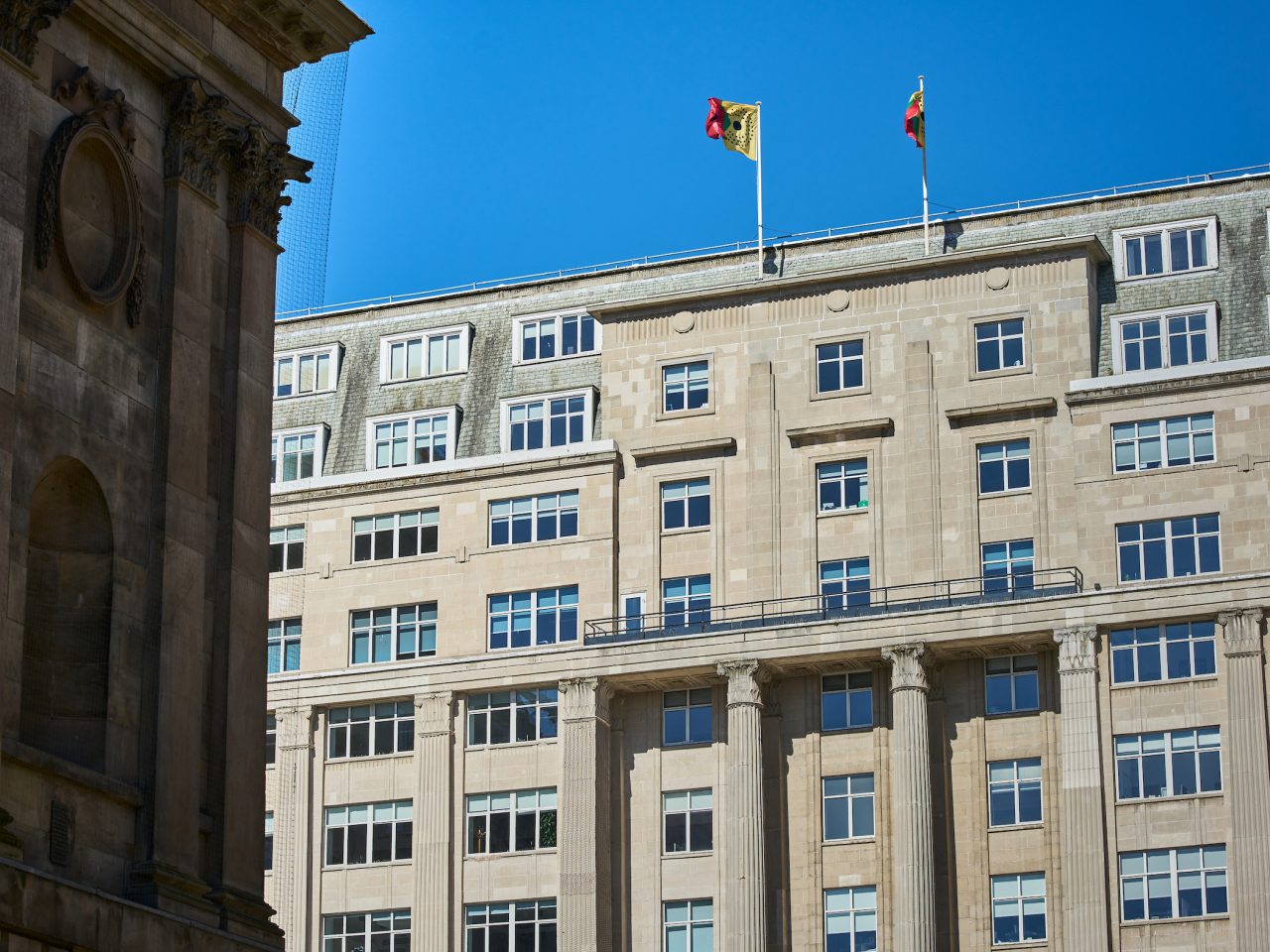 Two flags on the top of a building, flying in the wind