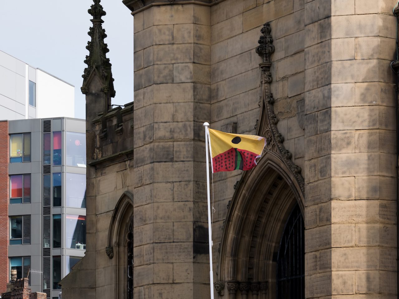 A flag designed by the artist, designed based on the colours of the african flag. The flag is yellow and red with a black and green figure.