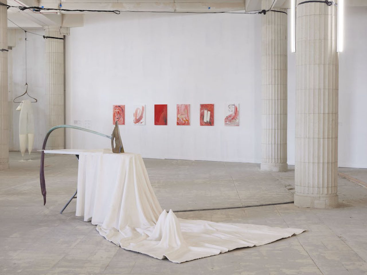 a sculpture that depicts an ironing board and iron with white fabric draping onto the floor and two rounded points raising from beneath.