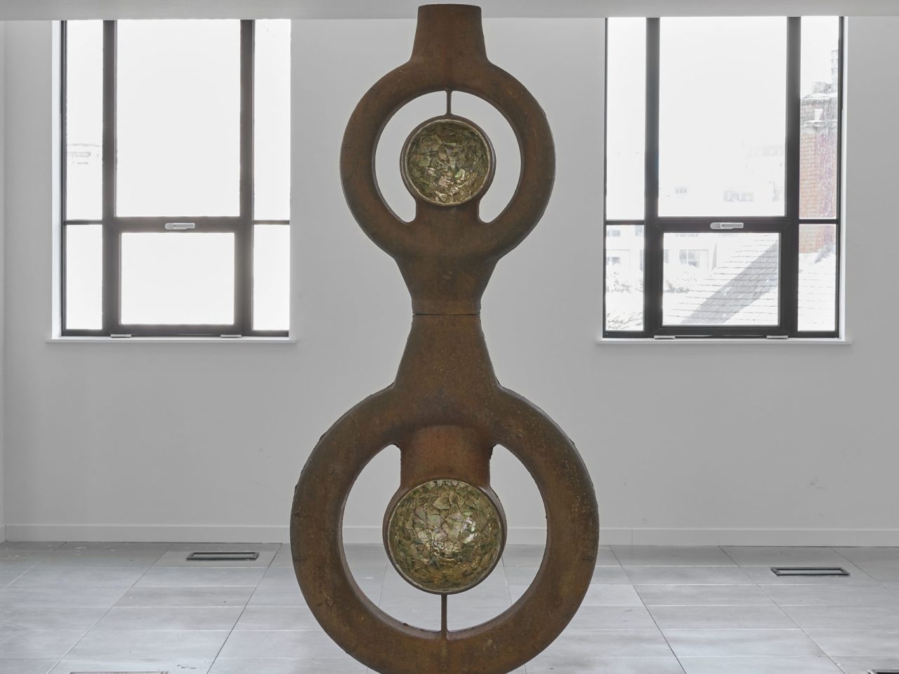 A seven-and-a-half-feet-tall circular iron structure. It has a rusty exterior contrasted by a smooth abalone shell interior.