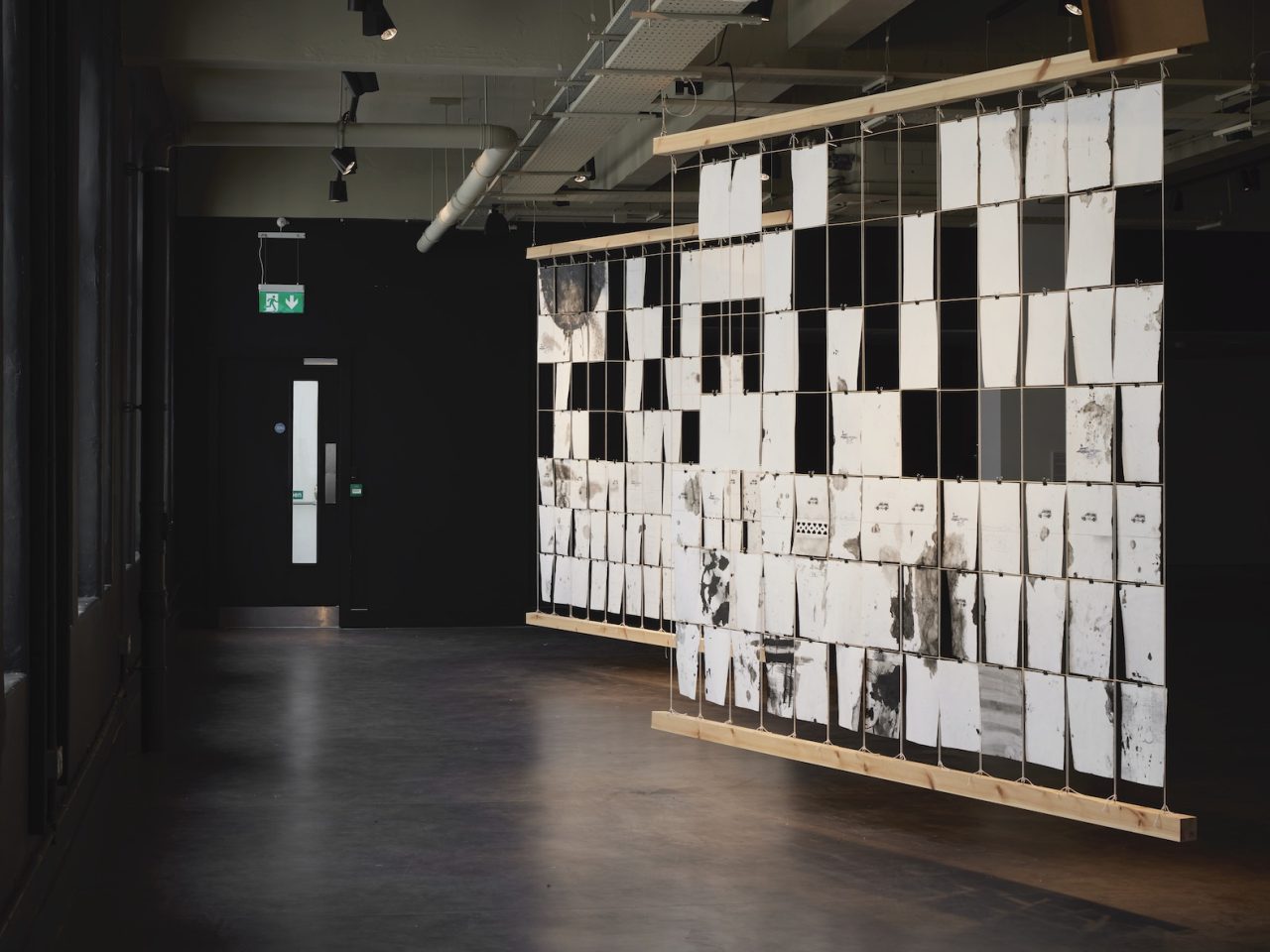 Black ink drawings on pieces of white paper stacked vertically, forming 2 hanging artworks