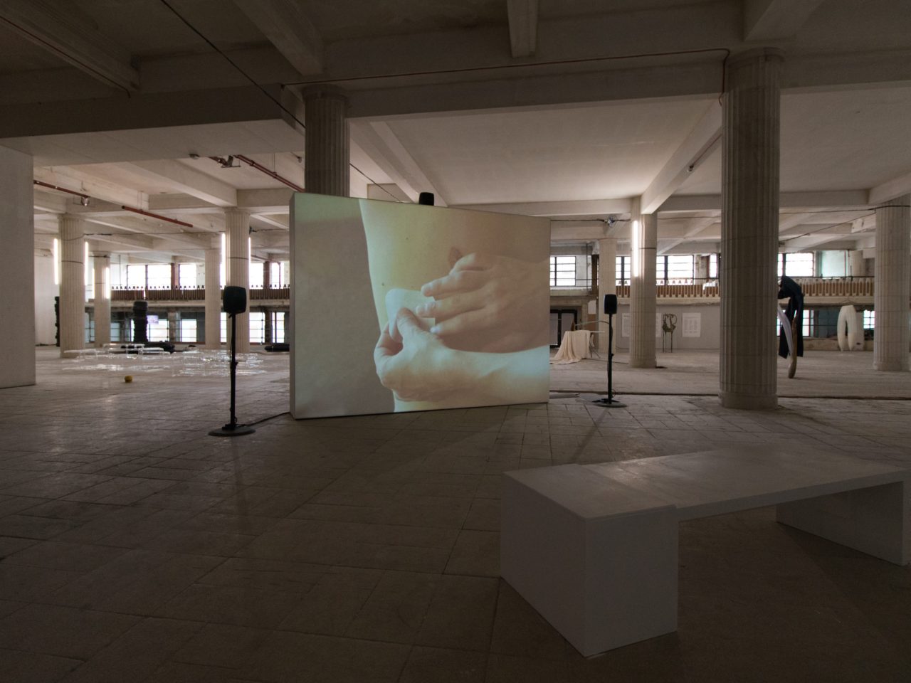 A free standing projector screen with a film still of someone putting a bandage on someones chest.