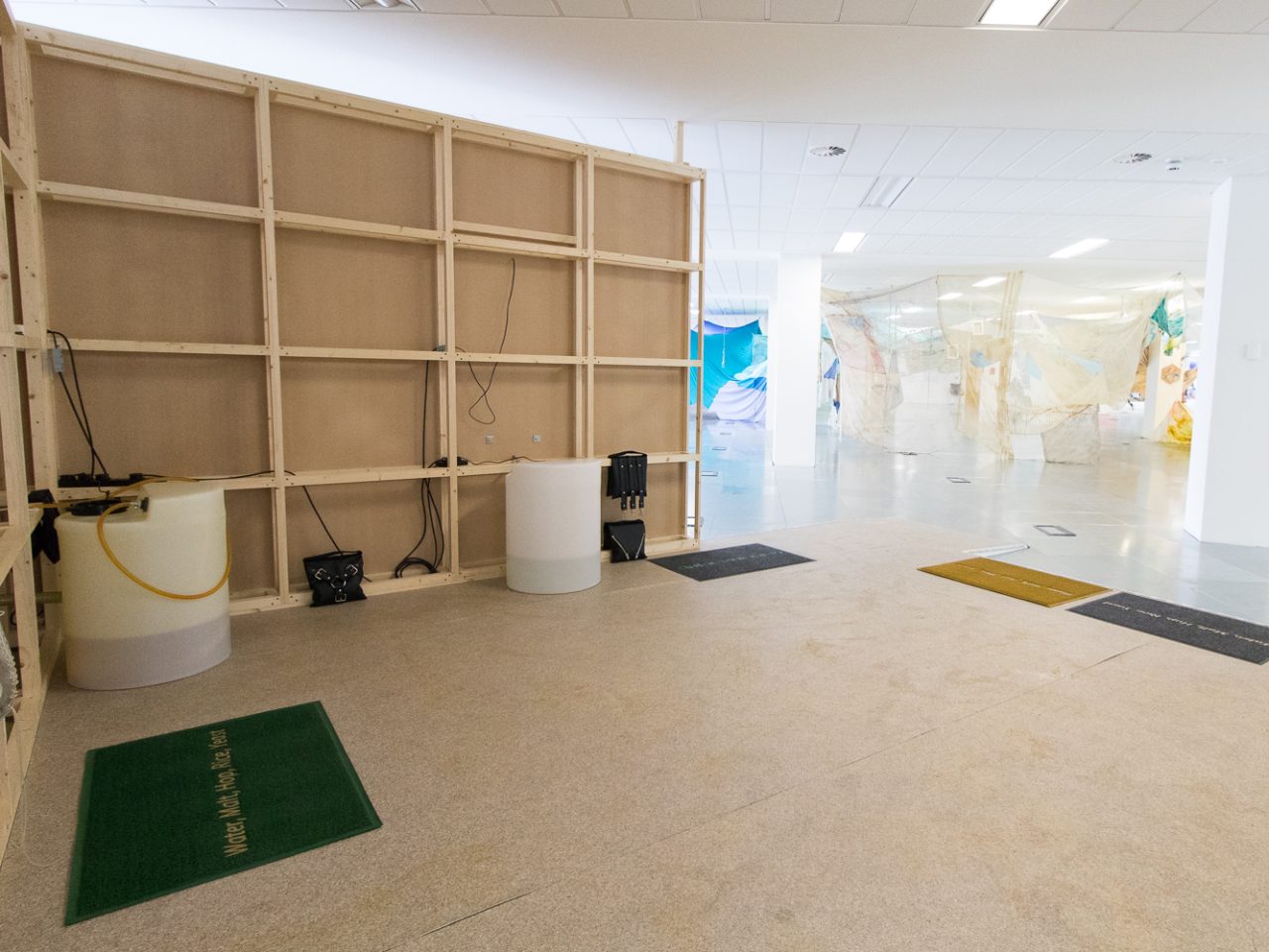 An installation of various mixed media elements, some including leather handbags and doormats.