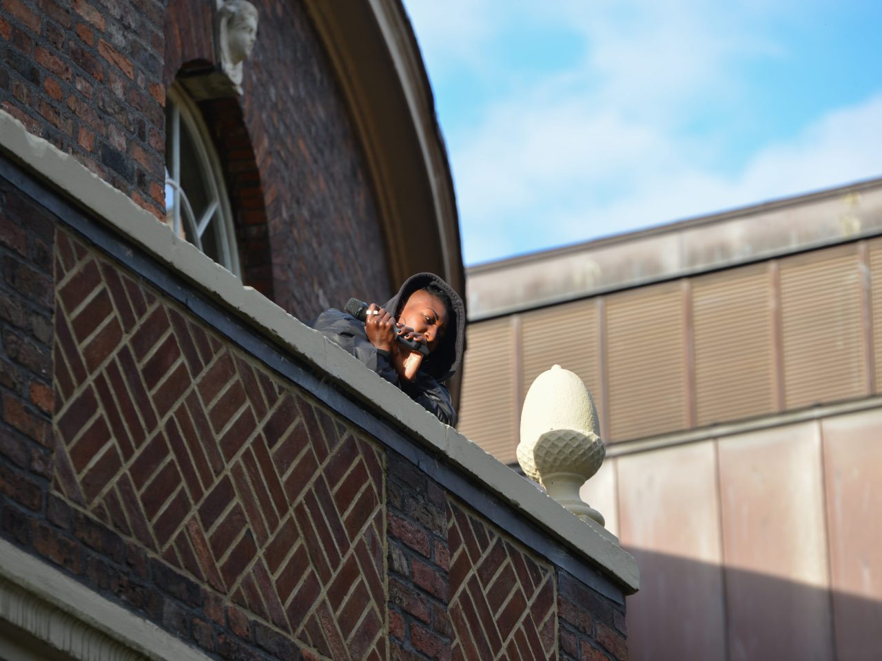 The artist on a bricked balcony looking down into the courtyard.