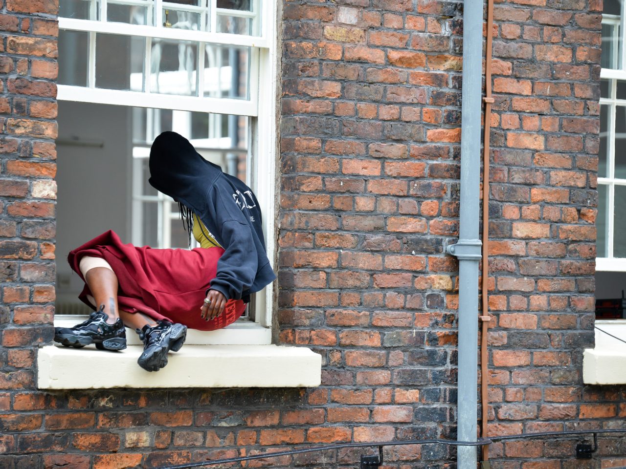 The artist climbing into the window from outside.