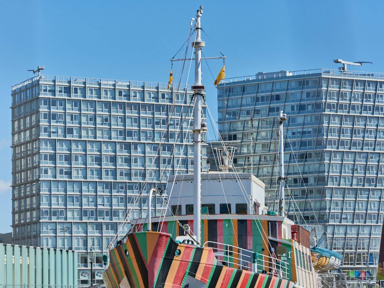 Two flags hanging from the top of a stripey boat on the Liverpool Albert Dock.