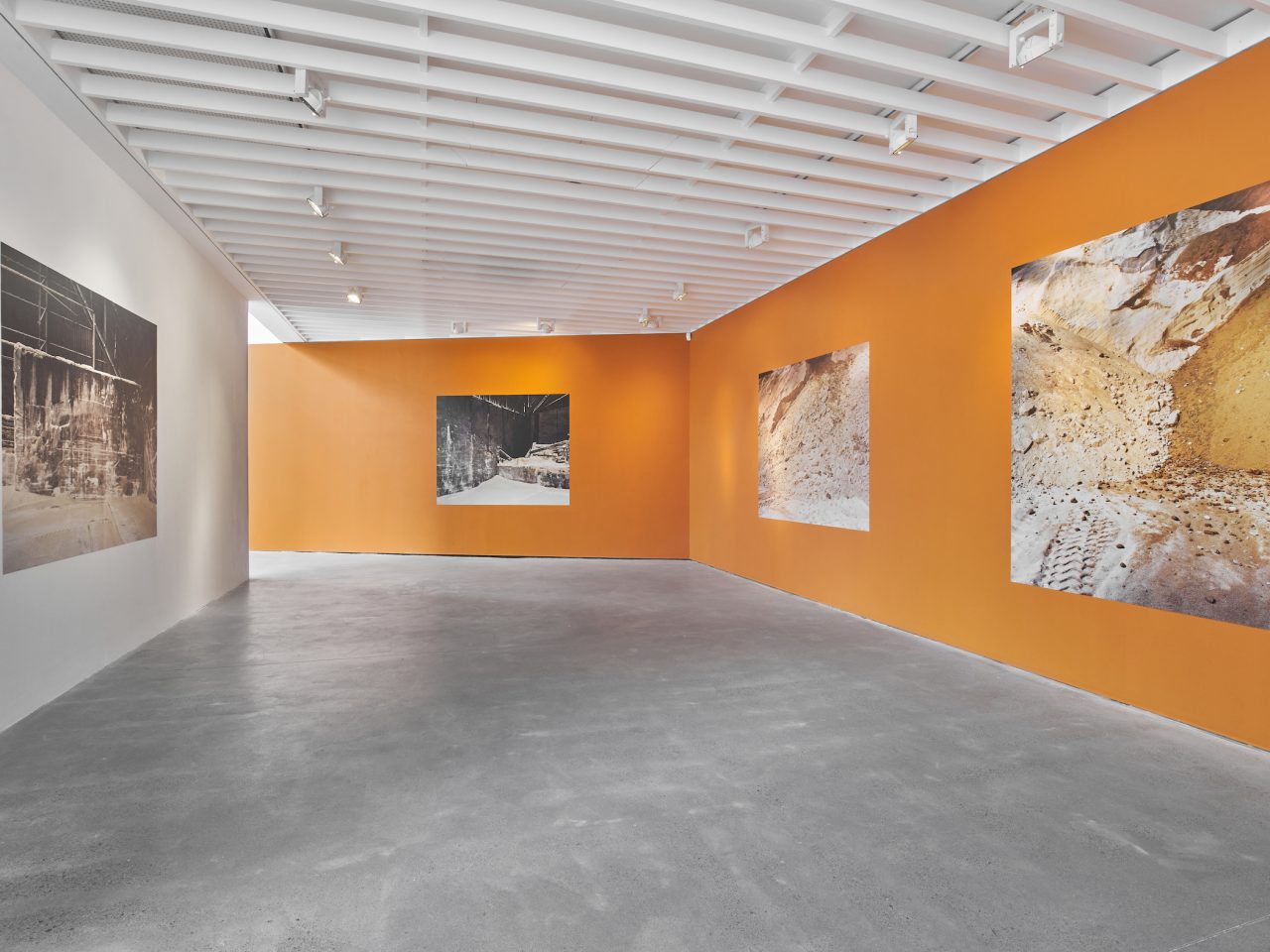 Four large vinyl stickers on a orange wall at Open Eye Gallery. The vinyl are photographs of the inside of a sugar factory.