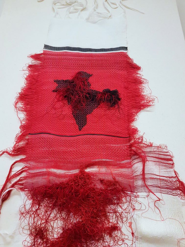 A thin tapestry coloured white, red and assets of black.